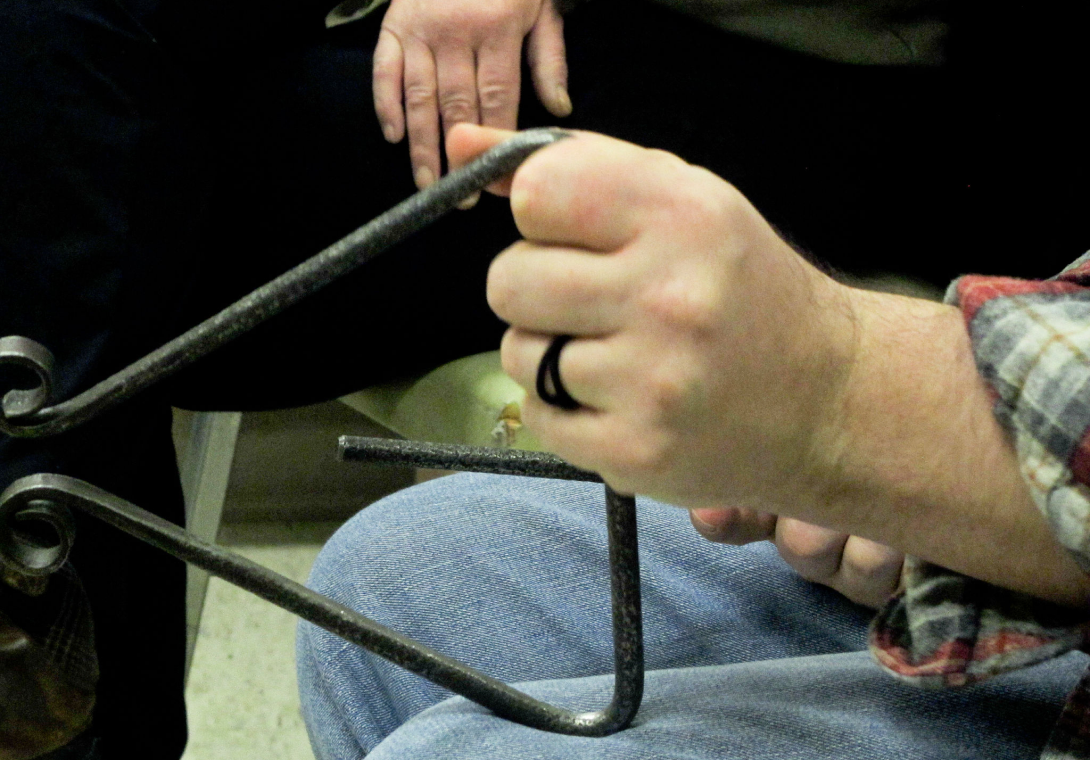 Person manipulating metal with pliers.